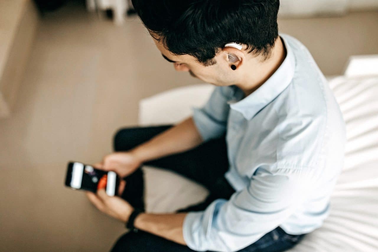 Business man with hearing aid checking his phone.