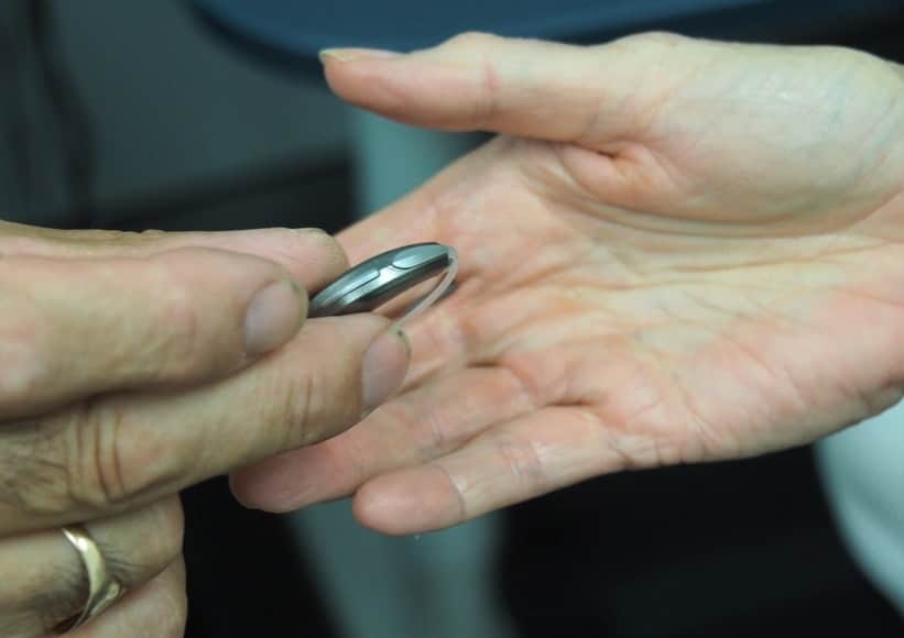 Close-up of a hand holding a hearing aid.