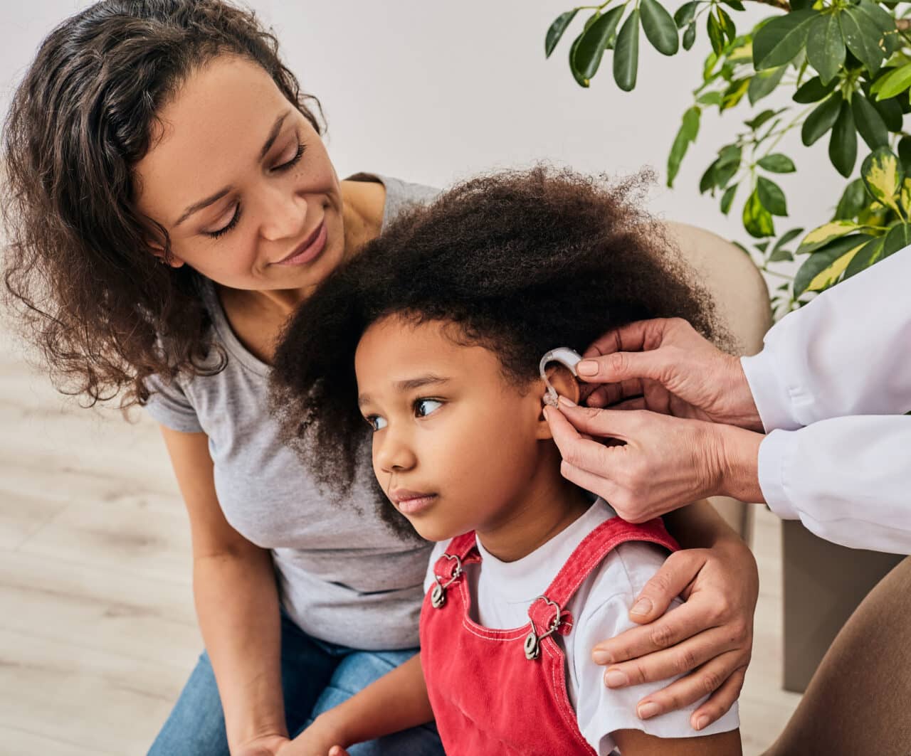 Young girl getting a hearing aid fitting with her mother by her side.