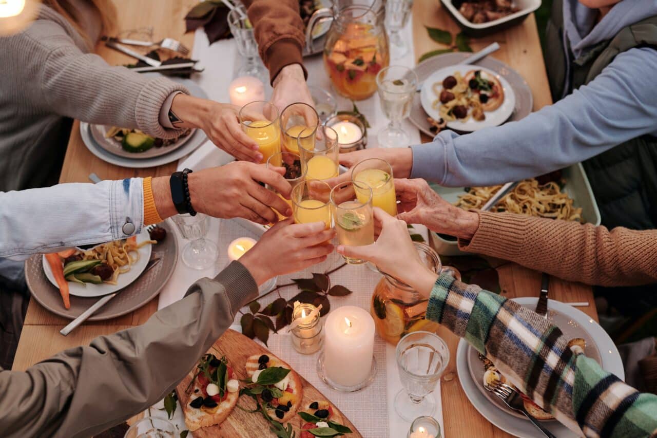 Group of people toasting with drinks at a dinner party.
