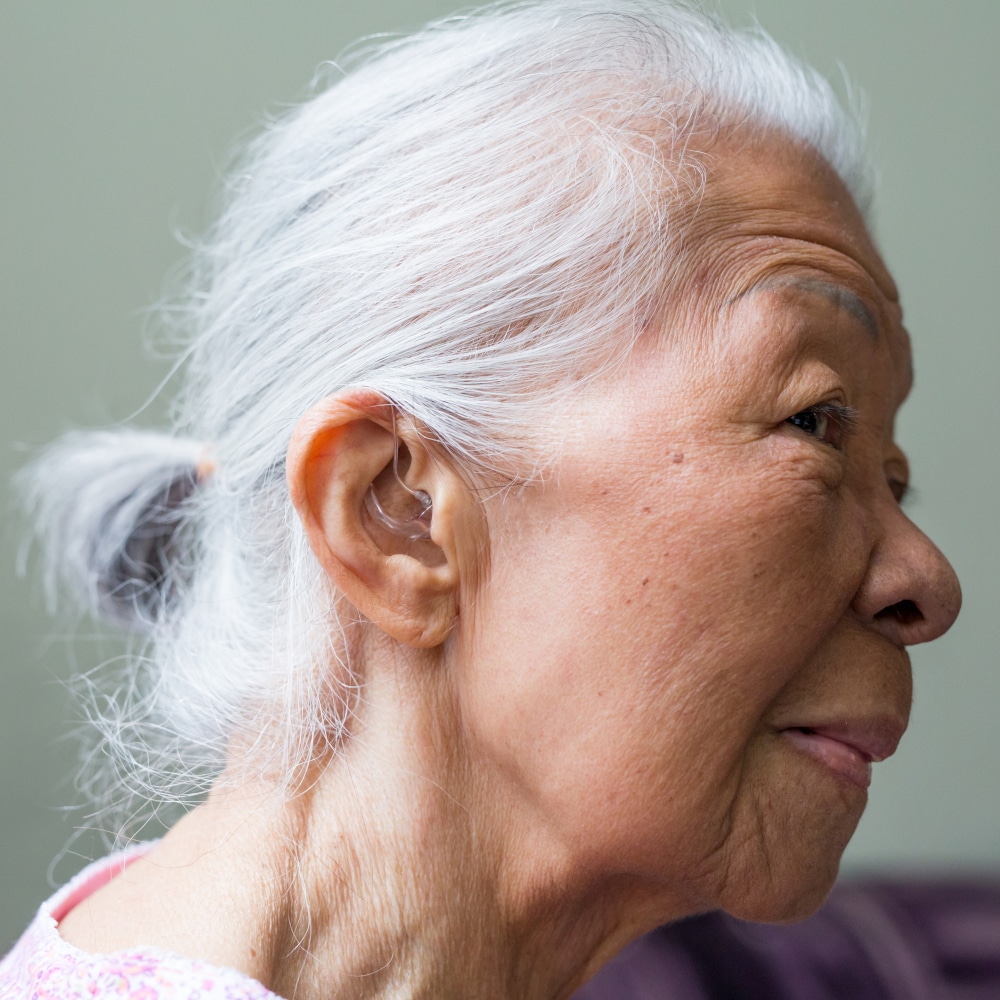 a woman waring a hearing aid shows her ear