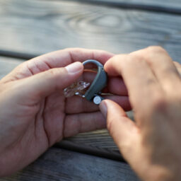 Close up of a person holding a hearing aid at a table