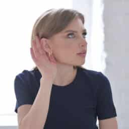 Woman witht her hand up to her ear trying to hear someone.jpg