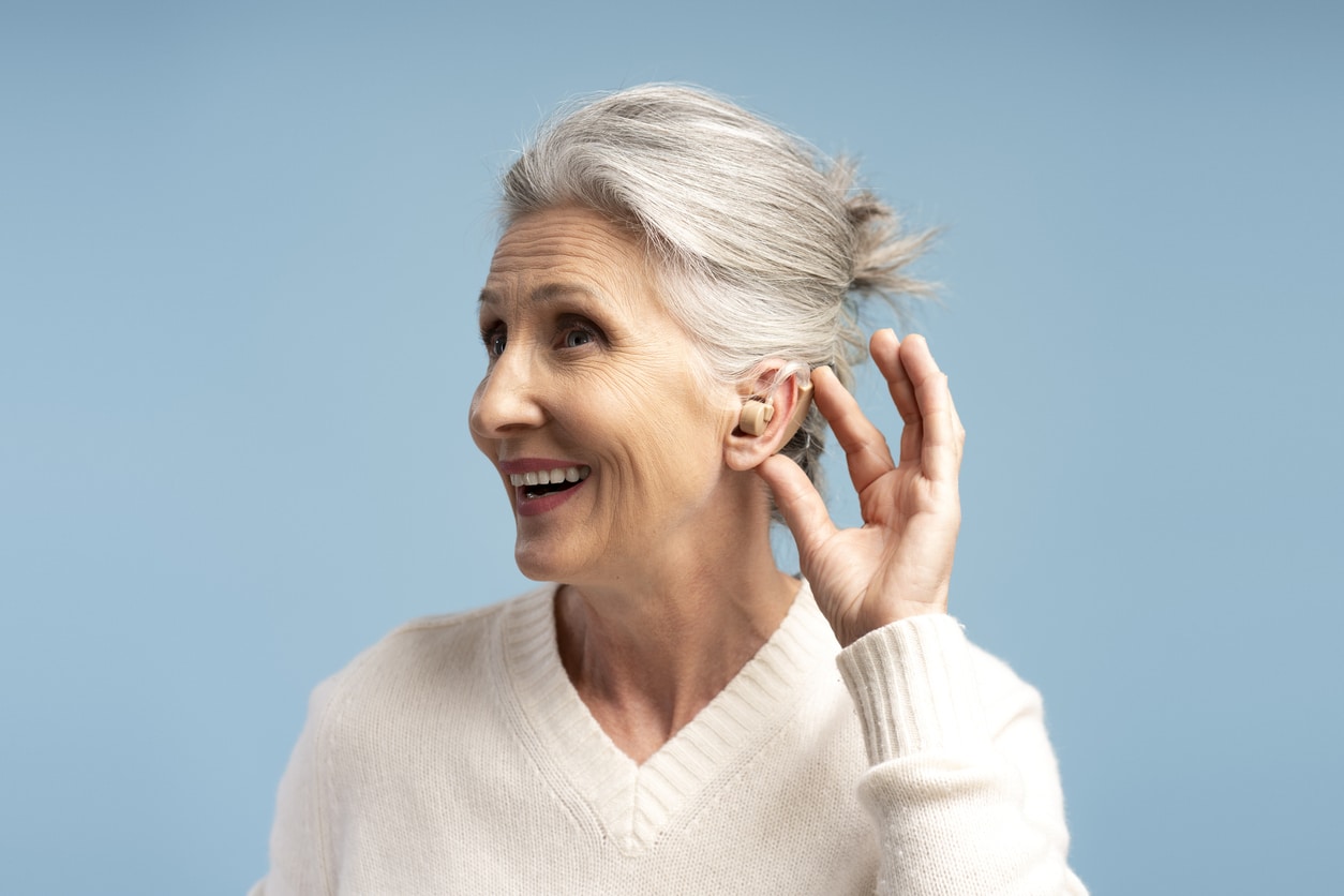 Happy senior woman showing off her hearing aid.